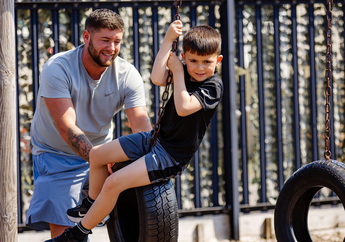 A man pushing a boy on a tyre swing